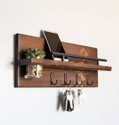 a wooden shelf with hooks and keys hanging on the wall next to a laptop computer