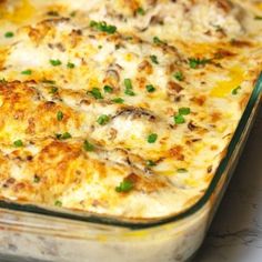 a casserole dish sitting on top of a table with green onions and cheese