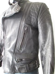 "Super 70s black biker jacket. Genuine leather. Made in Germany. It's a very solid jacket, with reinforced shouders and elbows (pic. 4-7), such as the bottom on backside (pic.8). Front black plastic zipper and mandarin collar that closes with velcro (pic.2). There are two front zipped pockets (pic.3) whose lining has to be repaired as it is unsewn. There are two other zipped pockets on waisband (pic.4-5). Two buckled straps on waistband. Quilted lining with inner pocket (pic.10). Very good condi Moto Leather Jacket For Motorcycling, Retro Biker Jacket With Zipper For Biker Events, Moto Leather Jacket With Zip Fly For Motorcycling, Motorcycling Moto Leather Jacket, Vintage Biker Jacket With Zipper For Biker Events, Mens Leather Biker Jacket, Black Biker Jacket, Classic Coats, Leather Biker Jacket