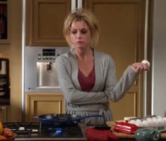 a woman is standing in the kitchen with eggs and an eggplant on the counter