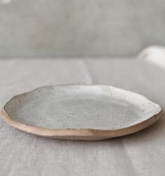 a white plate sitting on top of a table next to a gray cloth covered wall