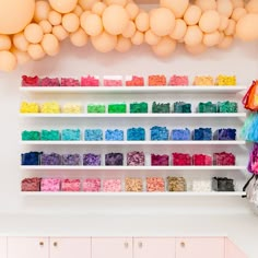 a room with shelves filled with lots of different colored items and balloons hanging from the ceiling