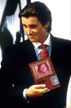 a man in a suit and tie holding up a book with an image on it