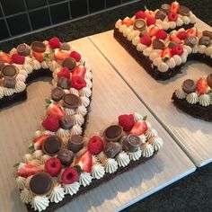 two heart shaped cakes with strawberries and chocolates on top, one has the letter d