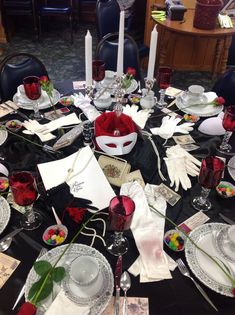 the table is set with white and red dishes, silverware, napkins, candles, and flowers