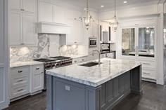 a large kitchen with marble counter tops and white cabinets, along with an island in the middle