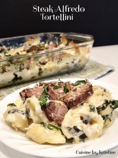 a white plate topped with pasta and meat covered in sauce next to a casserole dish