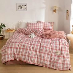 a bed with pink and white checkered comforter set on top of wooden floor