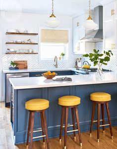 a kitchen with yellow stools and an island in front of the stove top oven