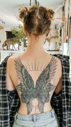 the back of a woman's body with an angel tattoo on her upper half