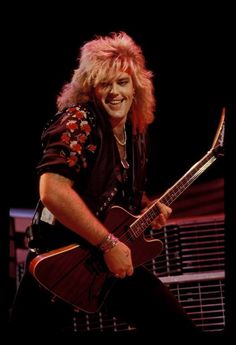 a man with blonde hair playing an electric guitar