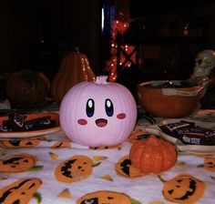 a pink pumpkin sitting on top of a table next to other plates and bowls filled with candy