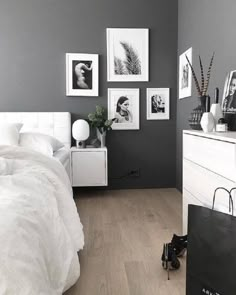 a bedroom with grey walls, white furniture and pictures on the wall above the bed