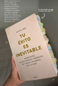 a person holding up a book in their hand with spanish writing on the front cover