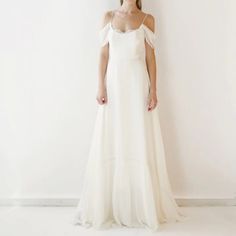 a woman standing in front of a white wall wearing a dress with ruffles