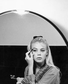 a woman is doing makeup in front of a mirror