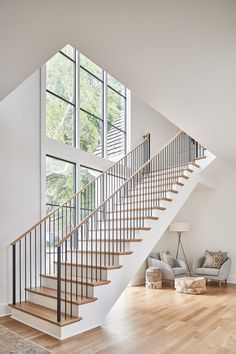 a living room filled with furniture and a stair case in front of a large window