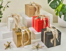 four gift boxes with ribbons tied around them and flowers in vases on the side