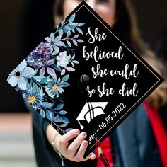 a woman wearing a graduation cap with flowers on it and she is holding her diploma