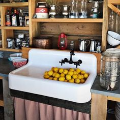 a white sink sitting under a wooden shelf filled with dishes