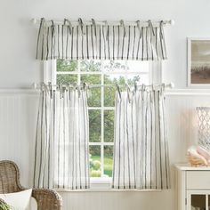 a living room filled with furniture and a window covered in striped drapes on the windowsill