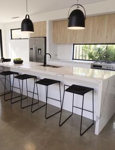 a dining room table surrounded by black chairs and an art piece hanging from the ceiling