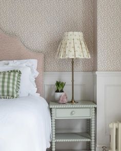 a white bed sitting next to a nightstand with a lamp on top of it