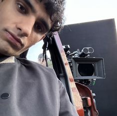 a man with curly hair sitting next to a guitar