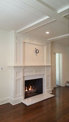 an empty living room with a fire place in the fireplace and hard wood flooring