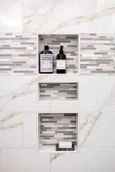 two white shelves with bottles on them in a bathroom