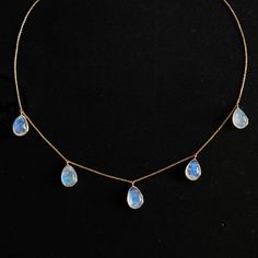 "ITEM DESCRIPTION: >>The necklace is made from Solid 14K Yellow Gold. Gemstone used is absolutely natural and ethically sourced. >>Natural Rainbow Moonstone with a beautiful blue sheen with bezel setting is studded on it with utmost precision. >>This is a minimalist design and is absolutely hassle-free and everyday jewelry. ✓ Gem: Rainbow Moonstone ✓ Gem size: 8x12mm (5 Pcs) ✓ Gem weight: 19.60 carats ✓ Gold purity: 14K (58.33% approx.) ✓ Gold weight: 2.28 grams ✓ Gross weight: 6.20 grams ✓ Neck Yellow Gold Moonstone Gemstone Necklace, Yellow Gold Moonstone Necklace With Gemstone, Moonstone Gemstone Necklace In Briolette Shape, Moonstone Briolette Gemstone Necklace, Dainty Blue Moonstone Jewelry, Blue Moonstone Teardrop Necklace, Rainbow Moonstone Necklace, Handmade Jewelry Box, Green Amethyst Ring