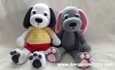 two crocheted stuffed dogs sitting next to each other on a white blanket with pink and gray paw prints