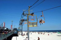 a ski lift going up the side of a beach next to a crowd of people