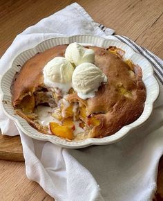 a pie with ice cream and peaches in it on a wooden table next to a fork