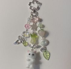 a keychain with charms attached to it on a white surface, including a small teddy bear