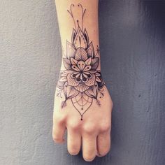 a woman's hand with a flower tattoo on the left side of her arm