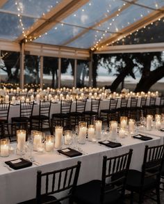 a long table is set up with candles and place settings for an outdoor wedding reception