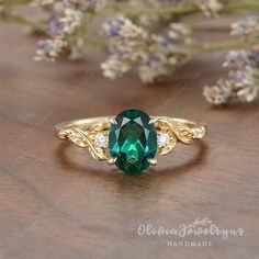 a green ring sitting on top of a wooden table next to some purple flowers and greenery