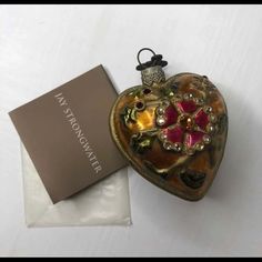 a heart shaped ornament sitting on top of a white table next to a box