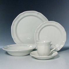 a white dinner set with two cups and saucers on the side, next to one another