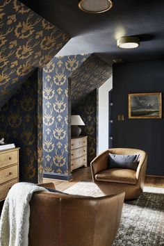 a living room filled with furniture and walls covered in blue wallpaper, along with a brown leather chair