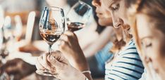 people sitting at a table with wine glasses in their hands