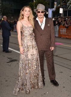 two people standing next to each other in front of a crowd at a red carpet event