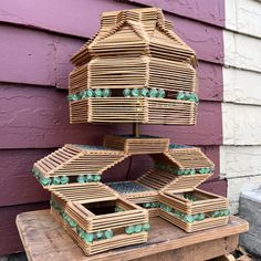 a bird house made out of wood with green beads on the top and bottom, in front of a purple building