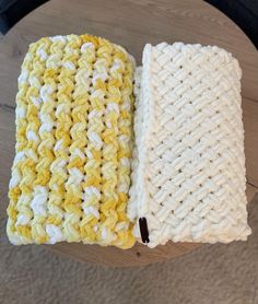 two crocheted dishcloths sitting on top of a wooden table next to each other