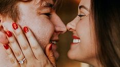 a close up of two people with red fingernails touching each other's foreheads