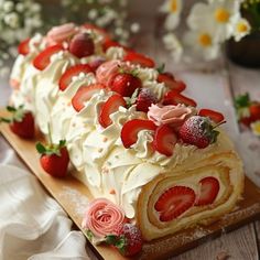 a cake with strawberries and cream frosting on a cutting board next to flowers