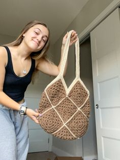 a woman is holding a crocheted purse in her hands and smiling at the camera