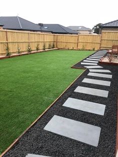 a backyard with artificial grass and stepping stones