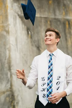 a young man wearing a blue and white tie throwing his graduation cap in the air